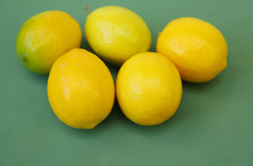 A pile of juicy lemons on a green background. Organic citrus fruits for a healthy diet. Close-up. Copy space.