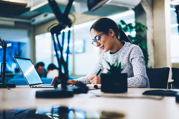 Professional female manager writing statement browsing information on laptop computer, woman...