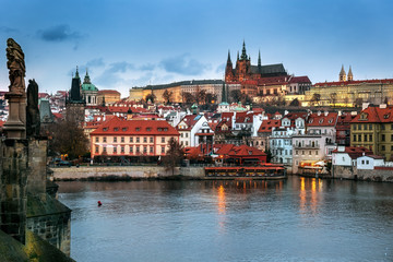 Naklejka na ściany i meble Illuminated Lesser town view from Charles Bridge in the evening, with Prague castle and Saint Nicholas church in Prague, Czechia