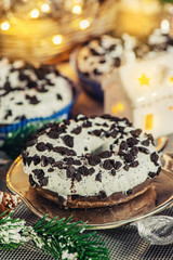 Pink and chocolate doughnuts lie on the Christmas table next to a candlestick. New year celebration
