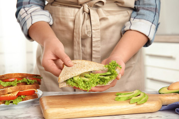 Woman making tasty sandwich at white marble table, closeup