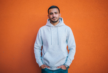 City portrait of handsome hipster guy with beard wearing gray blank hoodie or hoodie with space for...