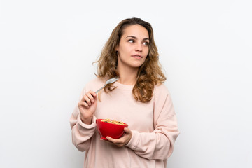 Young blonde woman holding a bowl of cereals and thinking