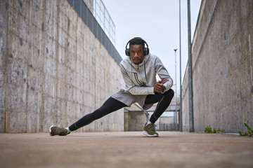 Athletic man is exercising near the grey wall