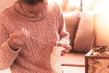 Young girl sews a button to her blouse