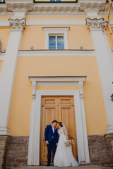 Fototapeta na wymiar The bride and groom kiss near a beautiful building