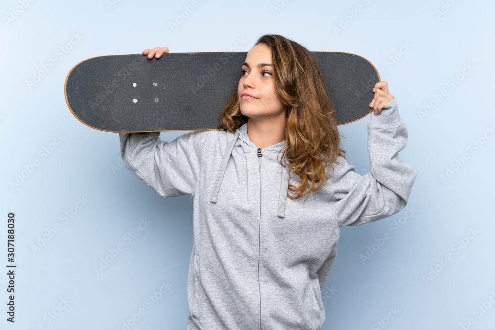 Wall mural young blonde woman with skate and looking side