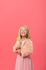 smiling and cute kid holding lollipop isolated on pink