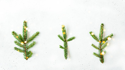 Christmas background with spruce branches with bokeh lights in a minimalist style on a white cement background. Top view with copy space.