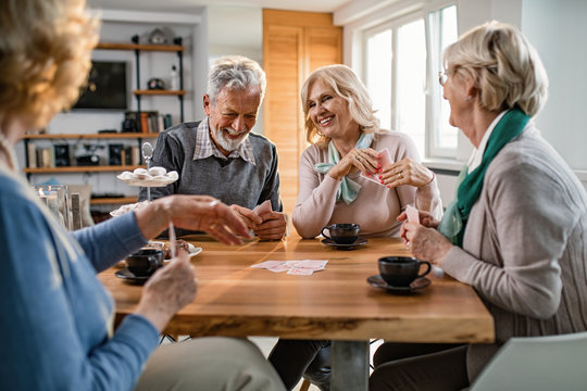 Happy Seniors Having Fun While Playing Cards In The Living Room.