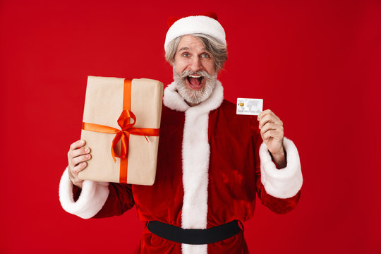 Image of happy old Santa Claus man holding gift box and credit card