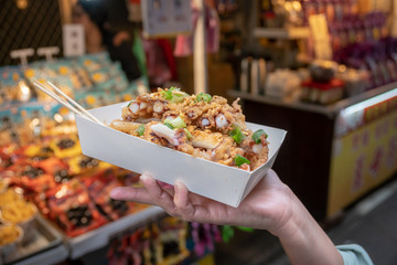 Fototapeta premium Selective focus of deep fried squid sliced topped with spring onion on paper box.