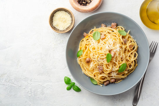 Classic spaghetti pasta carbonara with pancetta, egg yolk and parmesan cheese on concrete background. Top view, copy space.