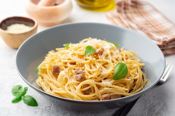 Classic spaghetti pasta carbonara with pancetta, egg yolk and parmesan cheese on concrete background. Selective focus.