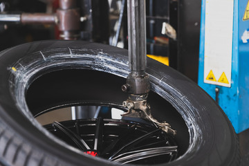 Wheel with tire on tire changing machine in auto repair service.