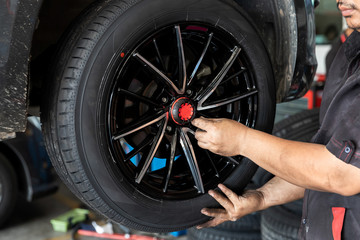 Fototapeta premium Car service, repair and maintenance concept - auto mechanic man changing tire in auto repair shop.