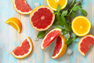 Ingredients for cooking a refreshing drink. Grapefruit, orange, ice and basil on a wooden table. Top view on a flat background.