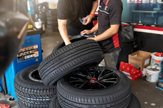 Car service, repair and maintenance concept - auto mechanic man changing tire in auto repair shop.