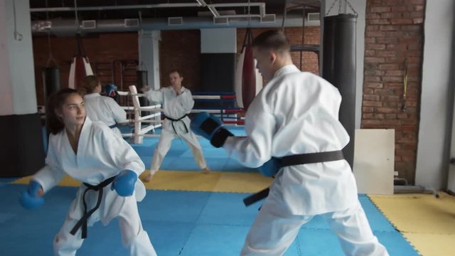 Medium shot of two pairs of sparring partners exercising in indoor gym