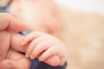 Hand of sleeping baby in the hand of mother close up on the bed, New family and baby protection concept