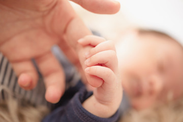 Hand of sleeping baby in the hand of mother close up on the bed, New family and baby protection concept