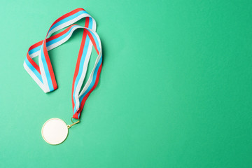 Gold medal on a ribbon, on a green background, top view