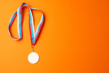 Gold medal on a ribbon, on an orange background, top view