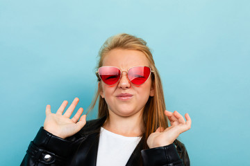 attractive european girl in a leather jacket in sunglasses on a light blue background