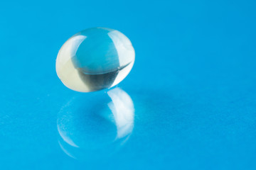 Transparent pill on a blue background, medicine, close up
