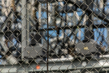 close up view on the exterior electric metal fence of an electrical substation, with a blurred view of the center elements in the background