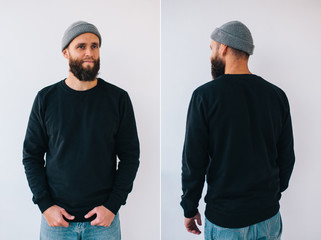City portrait of handsome hipster guy with beard wearing black blank hoody or sweatshirt with space...