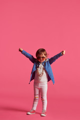 funny little girl in a beach hat and sun glasses on a pink background, studio shooting