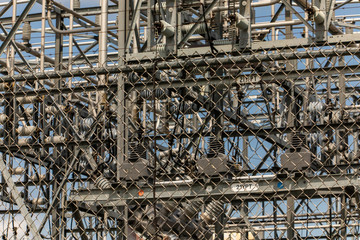 close up and selective focus view on the exterior metal fence of an electrical substation with high-voltage Elements in the background