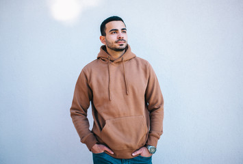City portrait of handsome hipster guy with beard wearing brown blank hoodie or hoody with space for your logo or design. Mockup for print