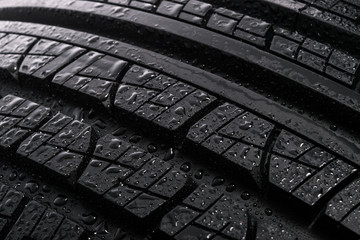 Surface of a new and modern multi season car tyre with water drops. Studio shot (high details)