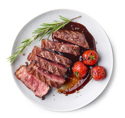 Grilled sliced Beef Steak with sauce, tomatoes and rosemary on a white plate Isolated on white background top view