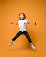 Fototapeta na wymiar Little funny child baby girl jumping happy smiling laughing in white t-shirt with text copy space 