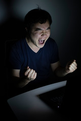 young man screams front pf laptop at night