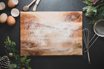 Christmas cooking or menu mock up. Empty cutting board and kitchen utensiles on dark background....