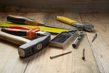 Metal hammer on a wooden handle, nails, corner for measurements, pliers, on an old workbench