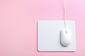 Modern optical wired mouse and white pad on pink background, top view. Space for text © New Africa