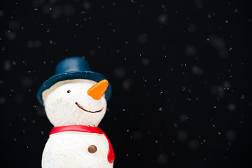 Happy smiley snowman wear blue hat and carrot nose standing with snowflakes in winter christmas...