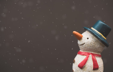 Happy smiley snowman wear blue hat and carrot nose standing with snowflakes in winter christmas...