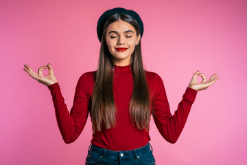 Calm girl in red relaxing, meditating. Woman calms down, breathes deeply with mudra om and shut...
