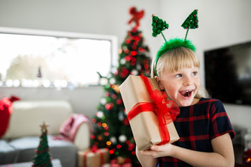 Young surprised girl holding christmas gift smiling