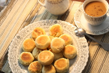 Artistic Delicious Indonesian Bakpia Yogyakarta Cookies Cake and Coffee Cappuccino Beverages for Breakfast in Wooden Rattan Table Background 