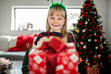 Young happy girl holding red christmas present