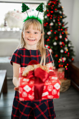 Young happy girl in christmas outfit holding present box