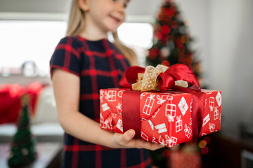 Young happy girl holding wrapped christmas present