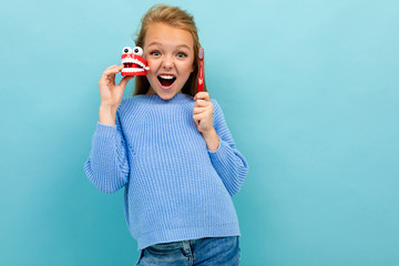 smiling european girl holding a toothbrush in her hands on a light blue background